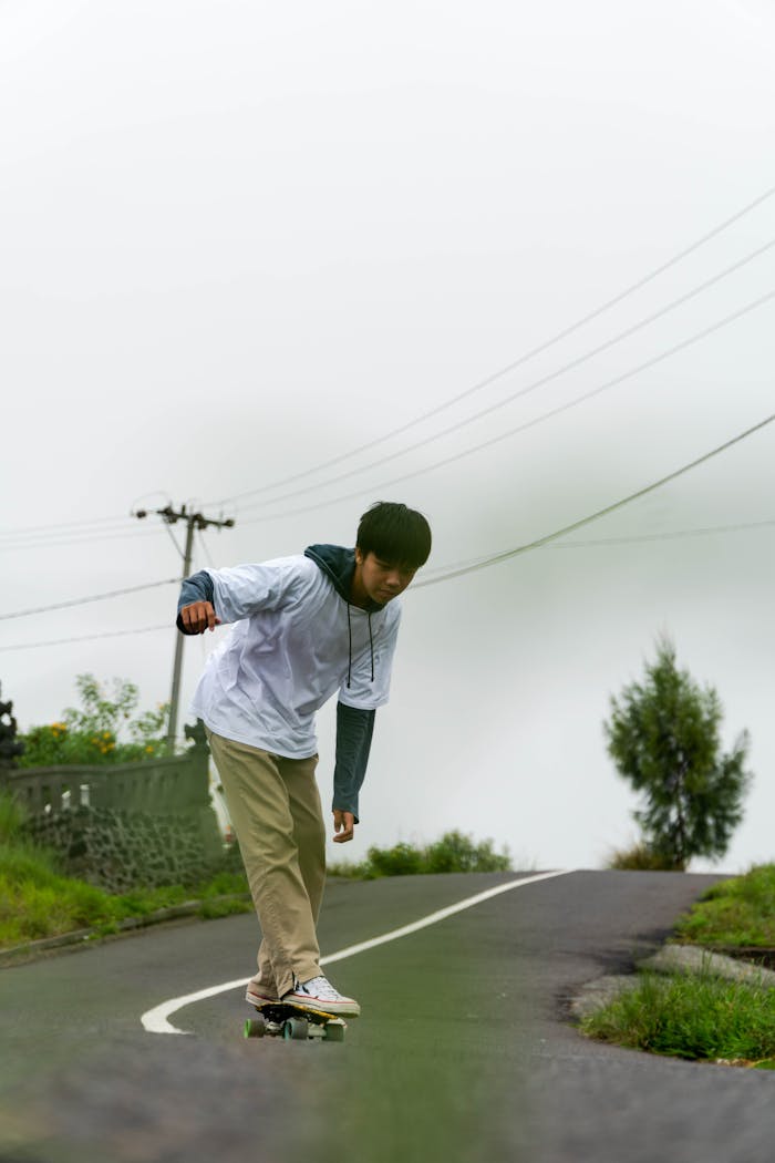 A young man skateboards along a scenic rural road in Bali, Indonesia, capturing outdoor adventure and leisure.