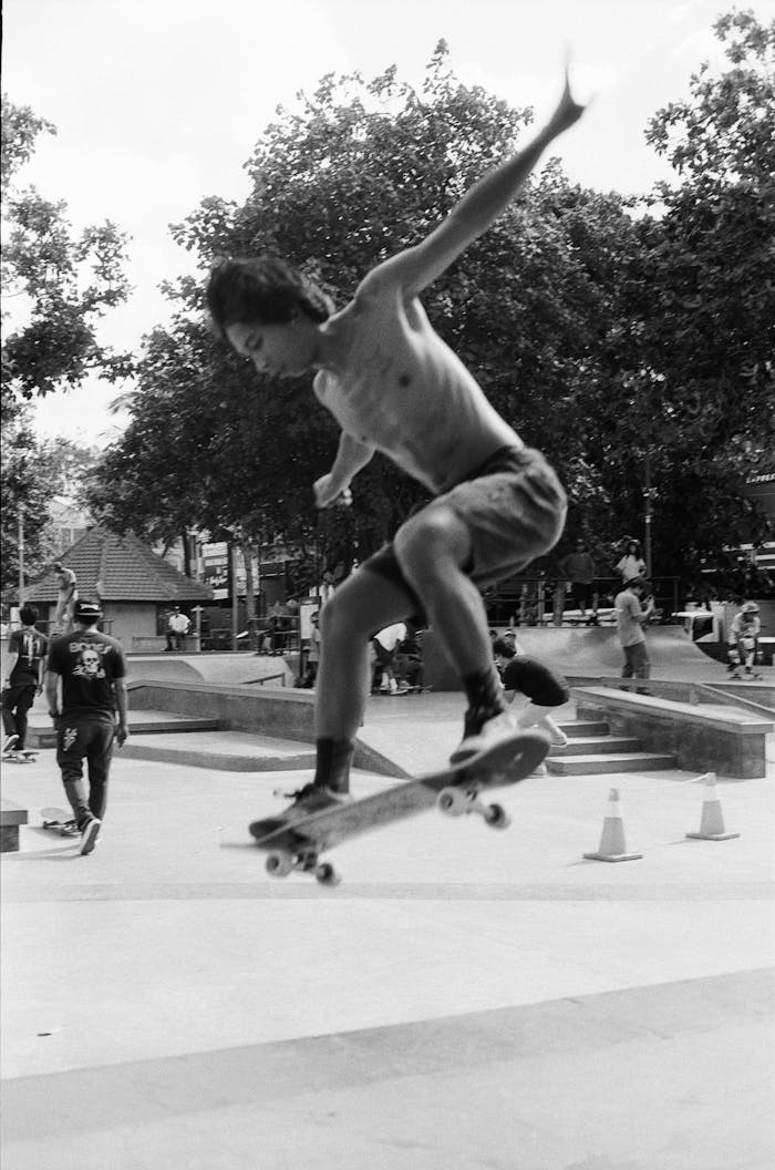 A skilled skateboarder mid-air at a bustling skate park in Bali, Indonesia.