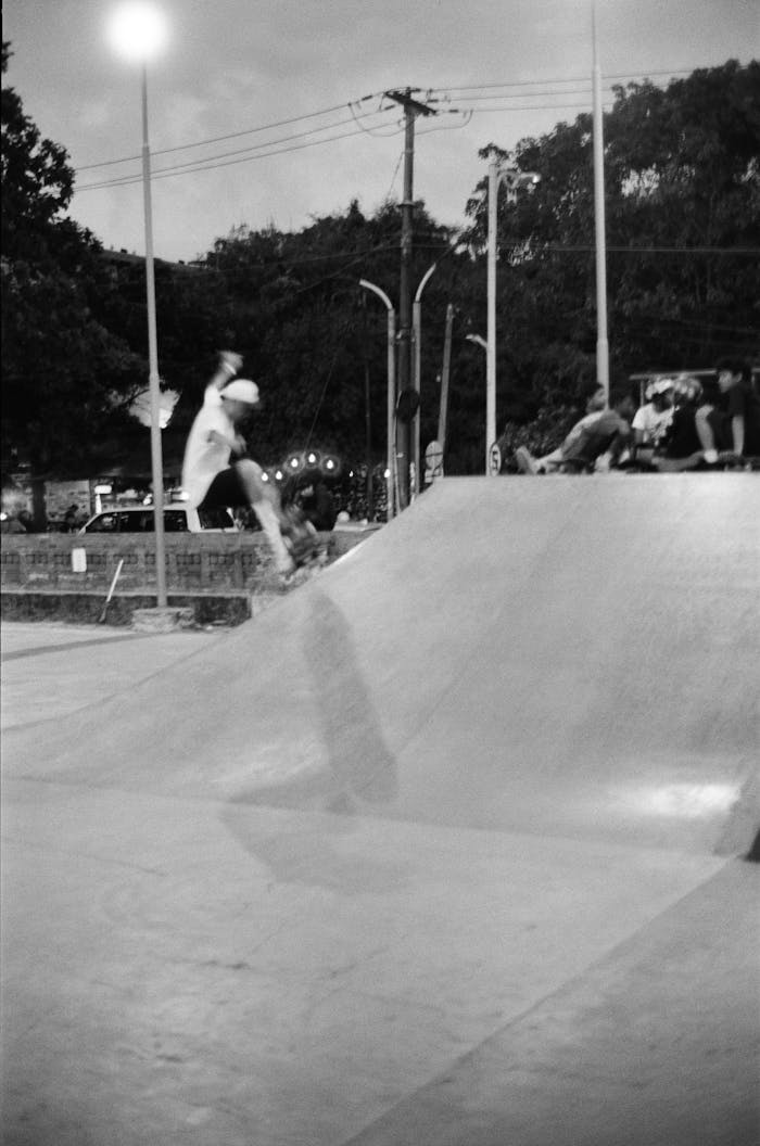 Black and white photo of a skateboarder performing a trick in a Bali, Indonesia skatepark at dusk.